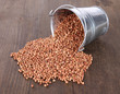 Overturned bucket with grains on wooden background