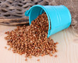 Overturned bucket with grains on wooden background