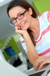Foto: Cheerful girl with eyeglasses working on laptop Cheerful girl with eyeglasses working on laptop