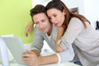 Cheerful couple looking at internet on tablet