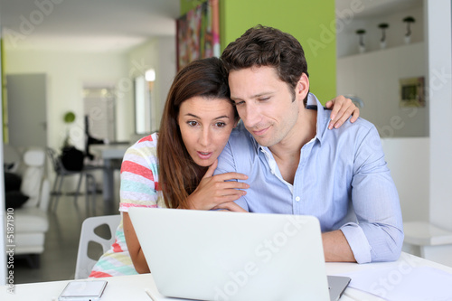 Photo: Couple at home sitting in front of laptop Couple at home sitting in front of laptop