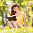 Young woman reading a book in the park with flowers