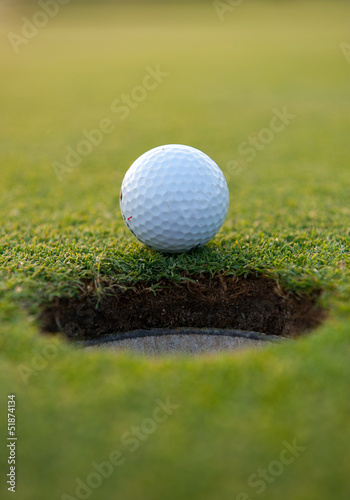 Photo: Golf ball by the hole Golf ball by the hole