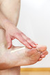A woman putting cream on her foot