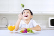 Photo: Happy boy eat brocoli in kitchen Happy boy eat brocoli in kitchen