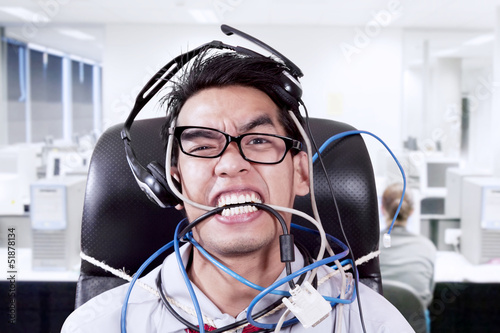 Photo: Stress businessman biting cables at office Stress businessman biting cables at office