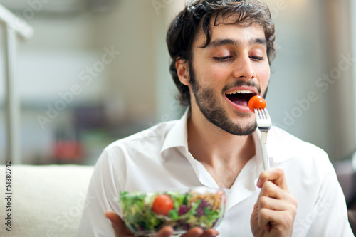 Photo: Man eating a salad on the sofa Man eating a salad on the sofa