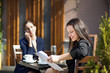 two business women sitting at a table in a cafe on the street