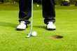 Golf player putting ball in hole