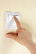 Hand switches on the lightswitch on the wall