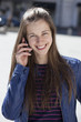 Young happy woman calling by phone on the street