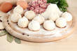 Raw dumplings and ingredients on wooden table