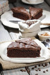 Chocolate cake on white plate, on hessian. Coffee beans on woode