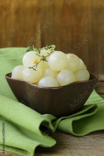 Photo: small pickled pearl onions on a wooden table small pickled pearl onions on a wooden table