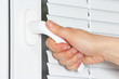 Hand opens the white plastic the window with jalousie