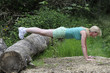 Woman keeping fit outdoors press ups using a log