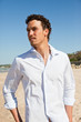 Handsome mediterranean young man with curly hair on the beach