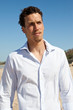 Handsome mediterranean young man with curly hair on the beach