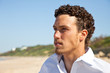 Handsome mediterranean young man with curly hair on the beach
