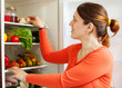 Young housewife near refrigerato