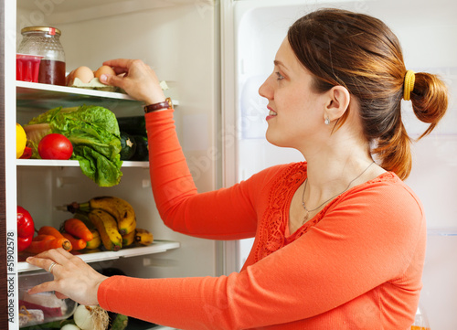 Photo: Young housewife near refrigerato Young housewife near refrigerato
