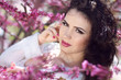 Beautiful brunette woman over pink brunch of tree, outdoors port