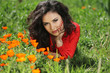 Woman in red resting on green grass, outdoors portrait