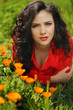 Woman in red resting on green grass, outdoors portrait