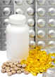 liquid capsules and silvery plates of medicines near a bottle..