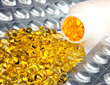 liquid capsules and silvery plates of medicines near a bottle..