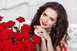 Attractive smiling girl with bouquet of red roses at modern inte