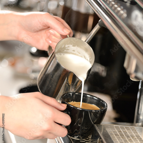 Photo: Waitress hands pouring milk making cappuccino Waitress hands pouring milk making cappuccino