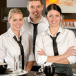 Photo: Three server posing in uniform in cafe Three server posing in uniform in cafe