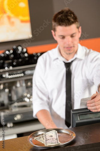 Photo: Young bartender in uniform taking cash dollar Young bartender in uniform taking cash dollar