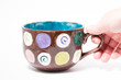 hand grabbing a painted mug in a studio
