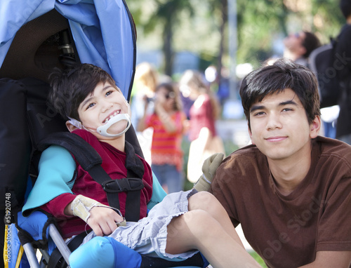 Photo: Big brother taking care of disabled little boy in wheelchair Big brother taking care of disabled little boy in wheelchair