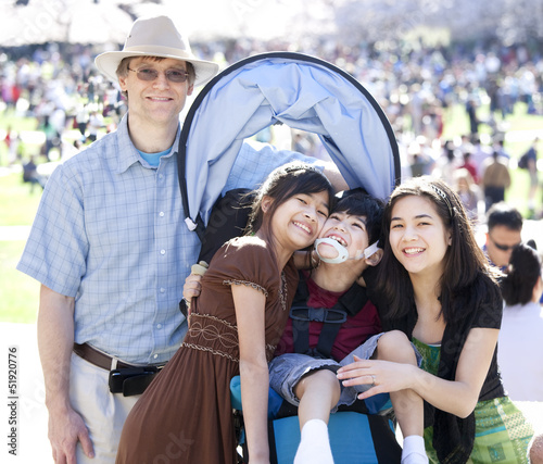 Photo: Large multiracial family in crowd with disabled child in wheelch Large multiracial family in crowd with disabled child in wheelch