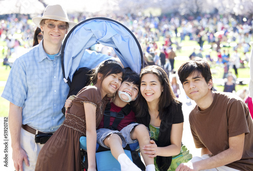 Photo: Large multiracial family in crowd with disabled child in wheelch Large multiracial family in crowd with disabled child in wheelch