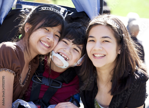 Photo: Disabled boy in wheelchair surrounded by big sisters, smiling Disabled boy in wheelchair surrounded by big sisters, smiling