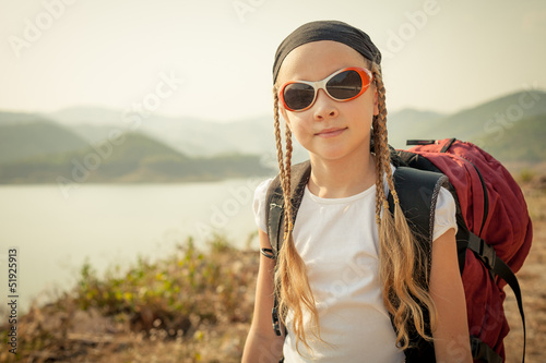 Photo: little girl with backpack afternoon on the lake shore little girl with backpack afternoon on the lake shore
