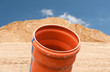 Ein KG-Rohr vor einem Sandhaufen und blauem Himmel