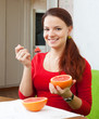 girl in red  eats grapefruit with spoon
