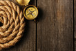Antique compass and rope over wooden background
