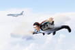 Young businessman flying with parachute on back
