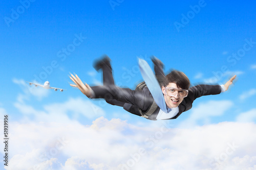 Photo: Young businessman flying with parachute on back Young businessman flying with parachute on back
