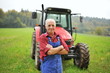 Proud farmer standing in front of his red tractor