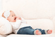 happy little baby girl laughing and sitting on a sofa in jeans