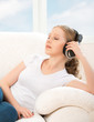 woman in headphones enjoys music while lying on the sofa at home