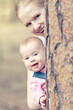 happy family in the park. Mom and toddler peeking from behind a