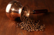 Coffee pot with coffee beans on brown wooden background